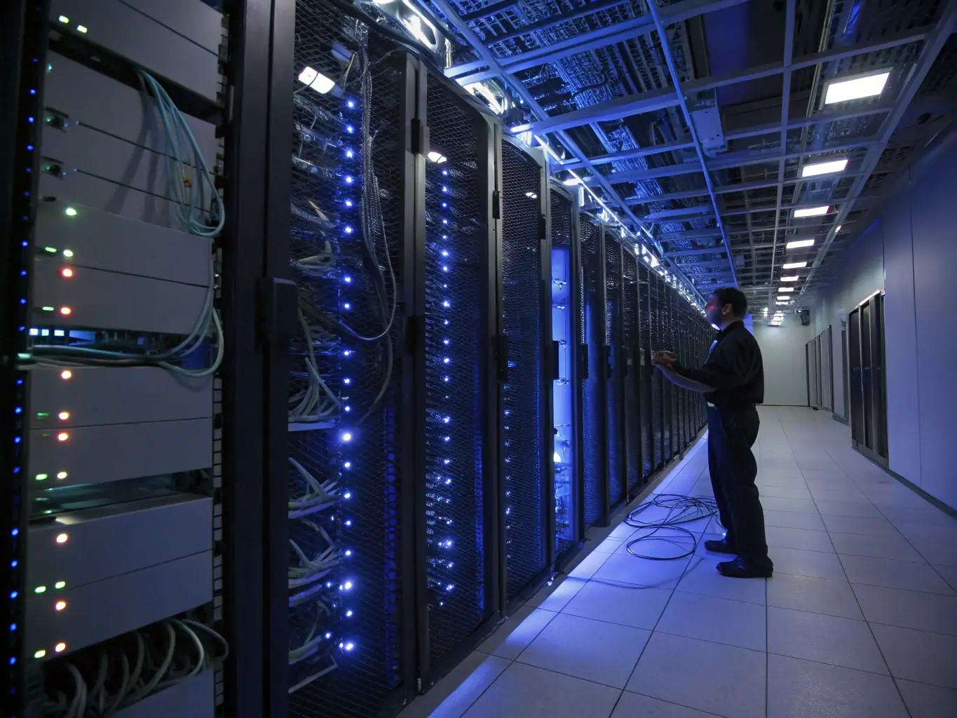 A network engineer is examining a server rack in a data center, with cables and blinking lights indicating network activity, representing the scalability of network solutions.